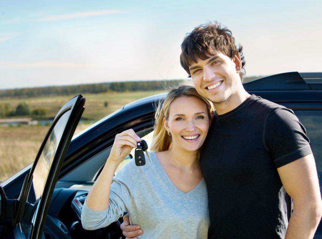 Happy young people near new car on nature portrait of happy bautiful couple showingh the keys standing near the car